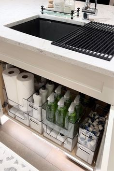 a kitchen sink filled with lots of bottles and paper towels