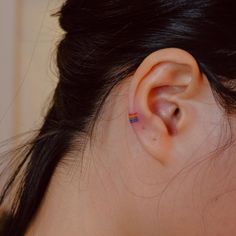 a woman's ear with a small red and blue stripe in the middle of it