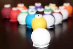 a row of colorful plastic balls sitting on top of a wooden table next to each other