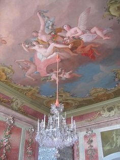 a chandelier hanging from the ceiling in a room with paintings on the walls