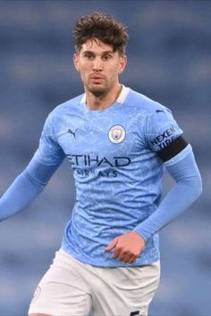 a soccer player is running with the ball in his hand and wearing a blue uniform