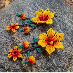 three beaded flowers sitting on top of a rock