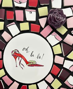 a plate with a shoe on it and a rose in the middle surrounded by small squares