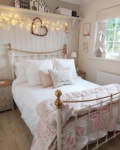 a white bed sitting in a bedroom next to a window with fairy lights on the headboard