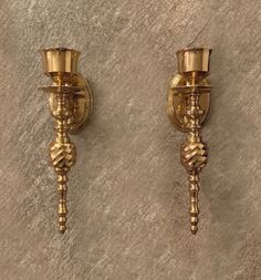 two brass candlesticks on a wall