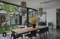 an image of a dining room table and chairs in front of large windows with trees outside