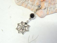 a silver spider web belly ring with black beads and a bead on the end