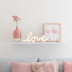 a living room filled with furniture and a love sign on top of a shelf next to a vase