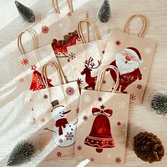 four bags with christmas designs on them sitting next to pine cones and fir trees,