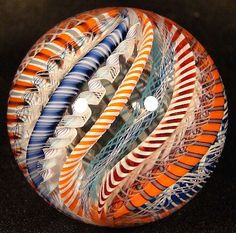 an orange, white and blue glass object sitting on top of a black surface