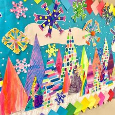 an art project is displayed on the wall with many different colors and shapes, including snowflakes