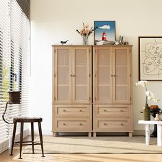 a wooden cabinet sitting in the middle of a living room next to a white table