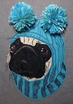 a pug wearing a blue hat with two pompoms