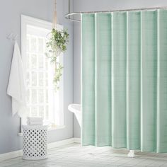 a white bath tub sitting next to a green shower curtain