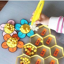 a child's hand is holding a yellow object over some honeycombs and flowers