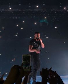 a man standing on top of a stage holding a microphone in front of an audience