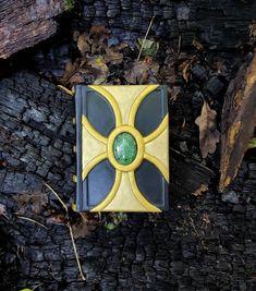 a yellow and black book sitting on top of a forest floor covered in leaves next to a tree