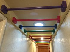 the hallway is lined with multicolored plastic pipes and lights on either side of the door