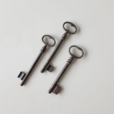 three old keys are sitting on a white surface