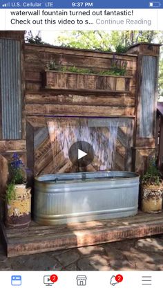 an outdoor water fountain made out of wood and metal buckets with plants growing in it