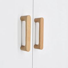 two wooden handles on white cupboards against a wall