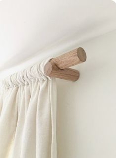 the curtain rod is attached to the wall by a wooden dowl and hangs on the side of the window