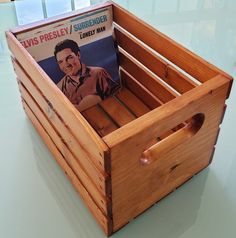 a wooden crate with a magazine holder on the top and an album in the bottom