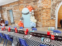 a table set up for a race themed birthday party with balloons and checkered cloths