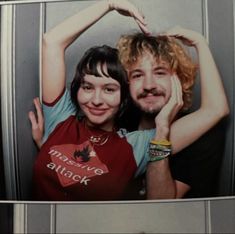 a man and woman posing for a picture in front of a mirror with their arms around each other