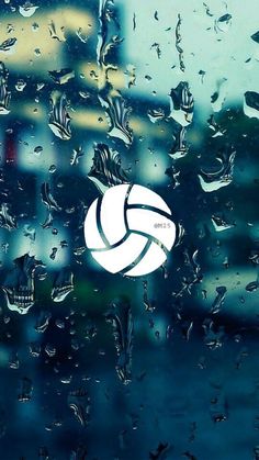 a volleyball ball sitting on top of a window covered in rain