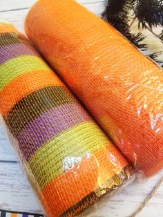 two carrots wrapped in plastic sitting next to each other on a white wooden table