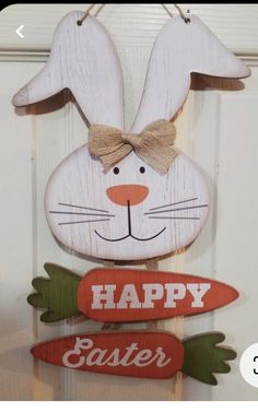 a wooden sign that says happy easter with a bunny on it's head and carrots hanging from the front door