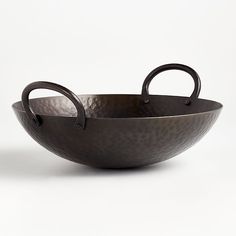 a large metal bowl with two handles on the side and an oval handle in the middle