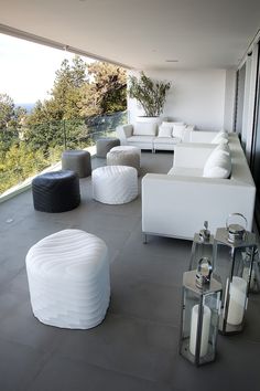 a living room filled with white furniture on top of a cement floor next to trees