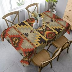 a dining room table covered with a colorful southwestern print cloth and four wooden chairs in front of a window