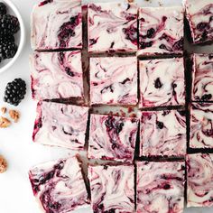 some blackberries are cut into squares and placed on a white surface next to nuts