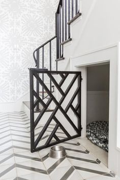 a dog bed underneath a stair case in a house with white walls and patterned flooring