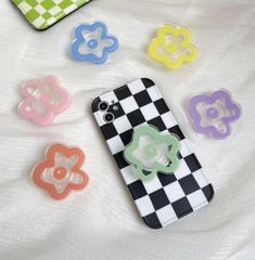 four cell phone cases sitting on top of a white bed covered in checkered fabric