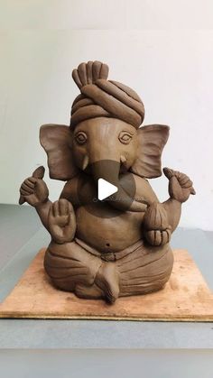 an elephant statue sitting on top of a wooden board with its trunk in the air