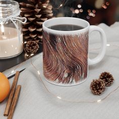 a coffee mug sitting on top of a table next to an orange and some cinnamon sticks