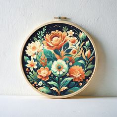 an embroidered floral design on a wooden hoop hanging from a wall above a white surface