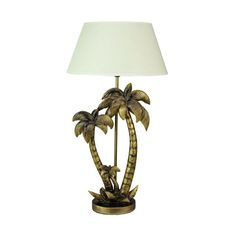 a lamp that has two palm trees on it and a white shade over the base