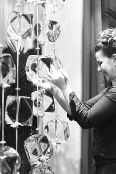 a woman standing next to a display of glass vases in front of a mirror