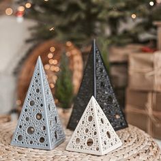 two black and white triangular shaped ornaments on a wicker table with christmas tree in the background