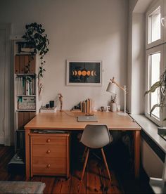 a desk with a chair, lamp and pictures on the wall in front of it