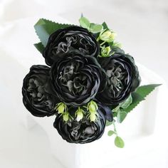 a bouquet of black flowers sitting on top of a white box