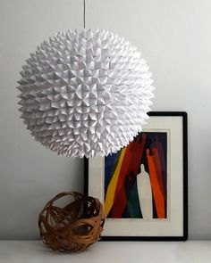 a large white ball hanging from the ceiling next to a basket and framed artwork on a wall