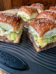 several sandwiches on a grill with sesame seeds and lettuce in between them, ready to be eaten