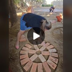 a woman standing over a fire pit made out of bricks