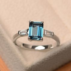 This ring features a 6*8 mm emerald cut London blue topaz and sterling silver finished with rhodium. Customization is available. It is made by hand, and it will take about 7 days to finish the ring after your payment is completed. Main stone: London blue topaz Main stone weight: Approx 2.01 ct Metal type: sterling silver finished with rhodium Accent stone: CZ Customization is available, I also can make it with 14k solid gold (white or yellow or rose) and diamond accent stone, just feel free to c Blue Topaz Ring Silver, London Blue Topaz Engagement Rings, Ring Emerald Cut, Blue Topaz Engagement Ring, Blue Gemstone Rings, Topaz Engagement Ring, London Blue Topaz Ring, Silver Anniversary, Emerald Engagement Ring Cut